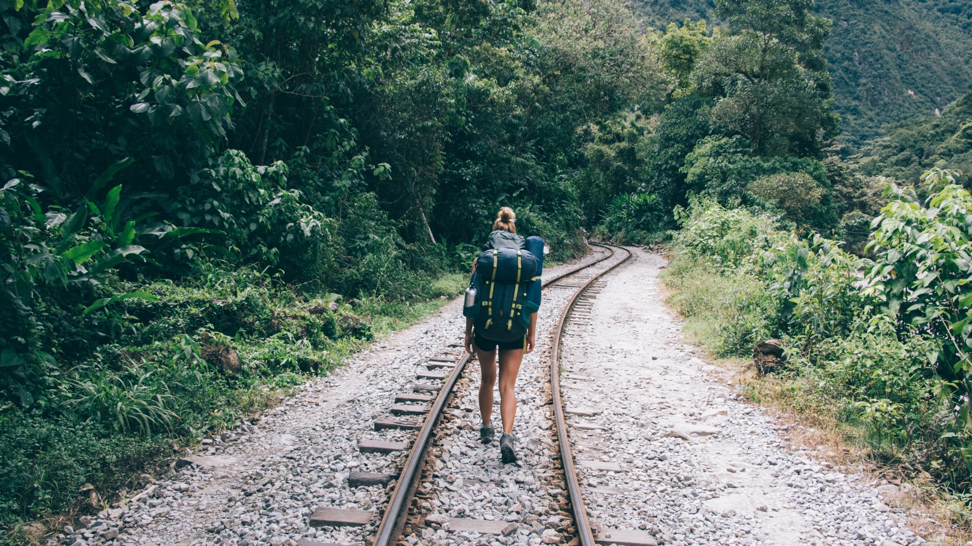 Backpacker walking railway track to Machu Picchu through jungle